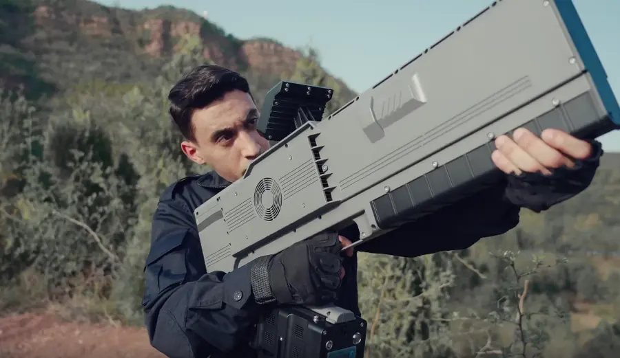 Operator carrying a Skyner Raptor handheld counter-drone system in the field